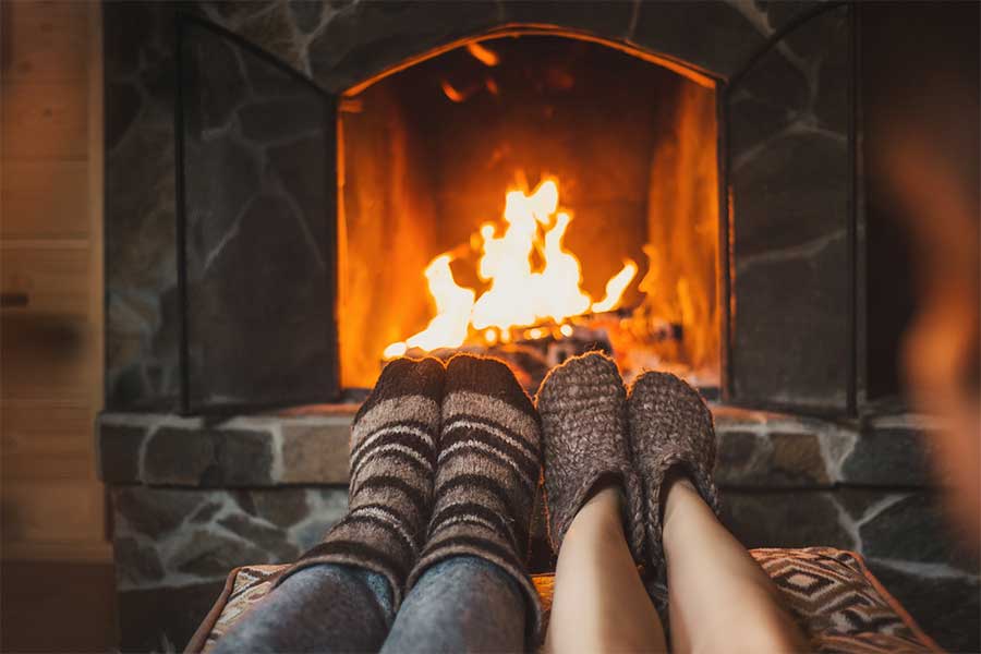 Couple warming their feet in front of a roaring open fire